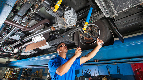 RV repair technician working on the undercarriage of a motorhome at a repair facility
